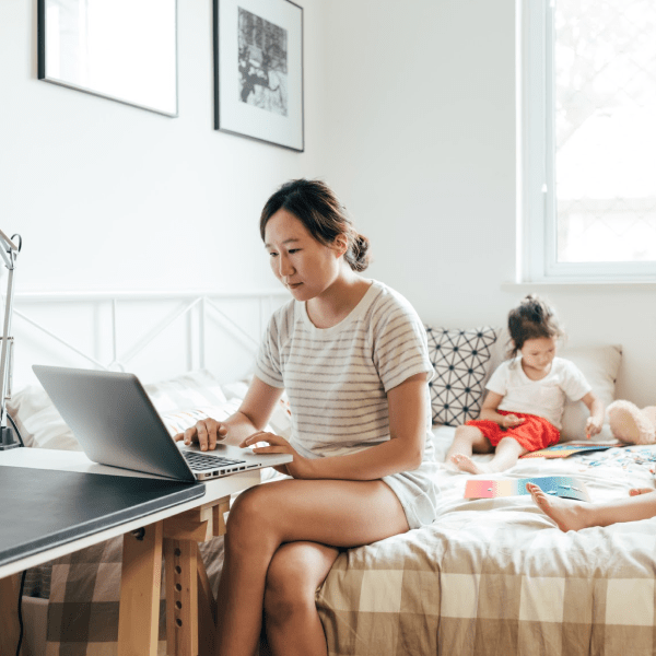 Woman works on her laptop while children are playing nearby.